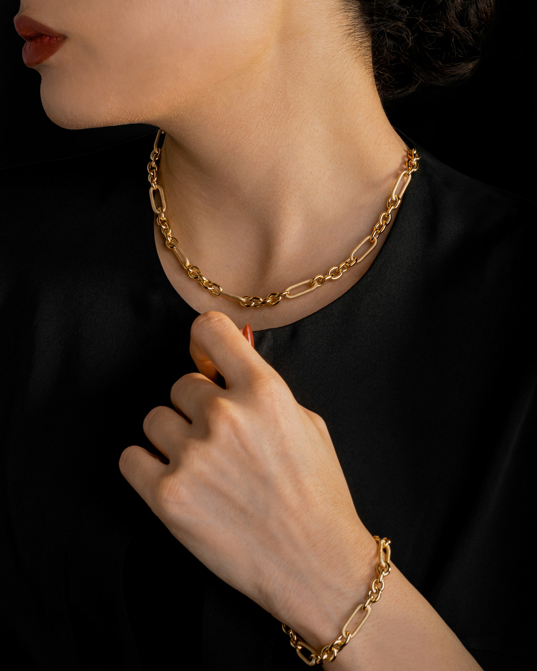 Modelo luciendo collar y pulsera de cadena de oro Aurum, editorial en fondo negro