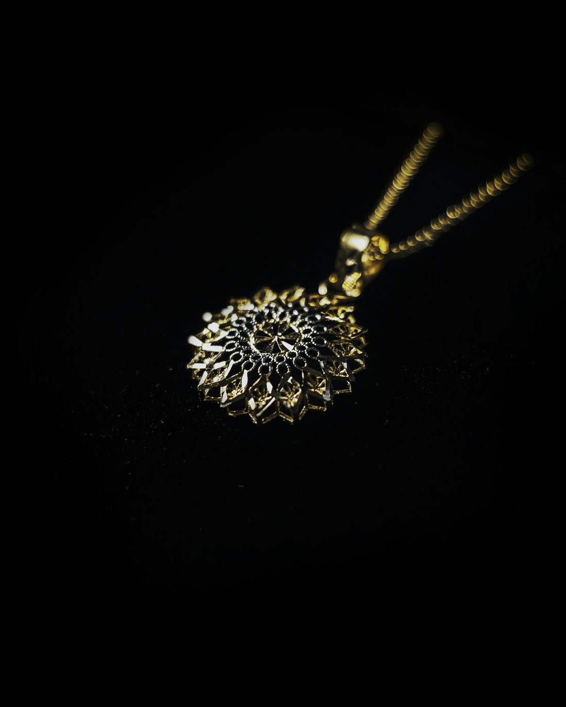 Colgante de oro tipo mandala sobre fondo negro absoluto